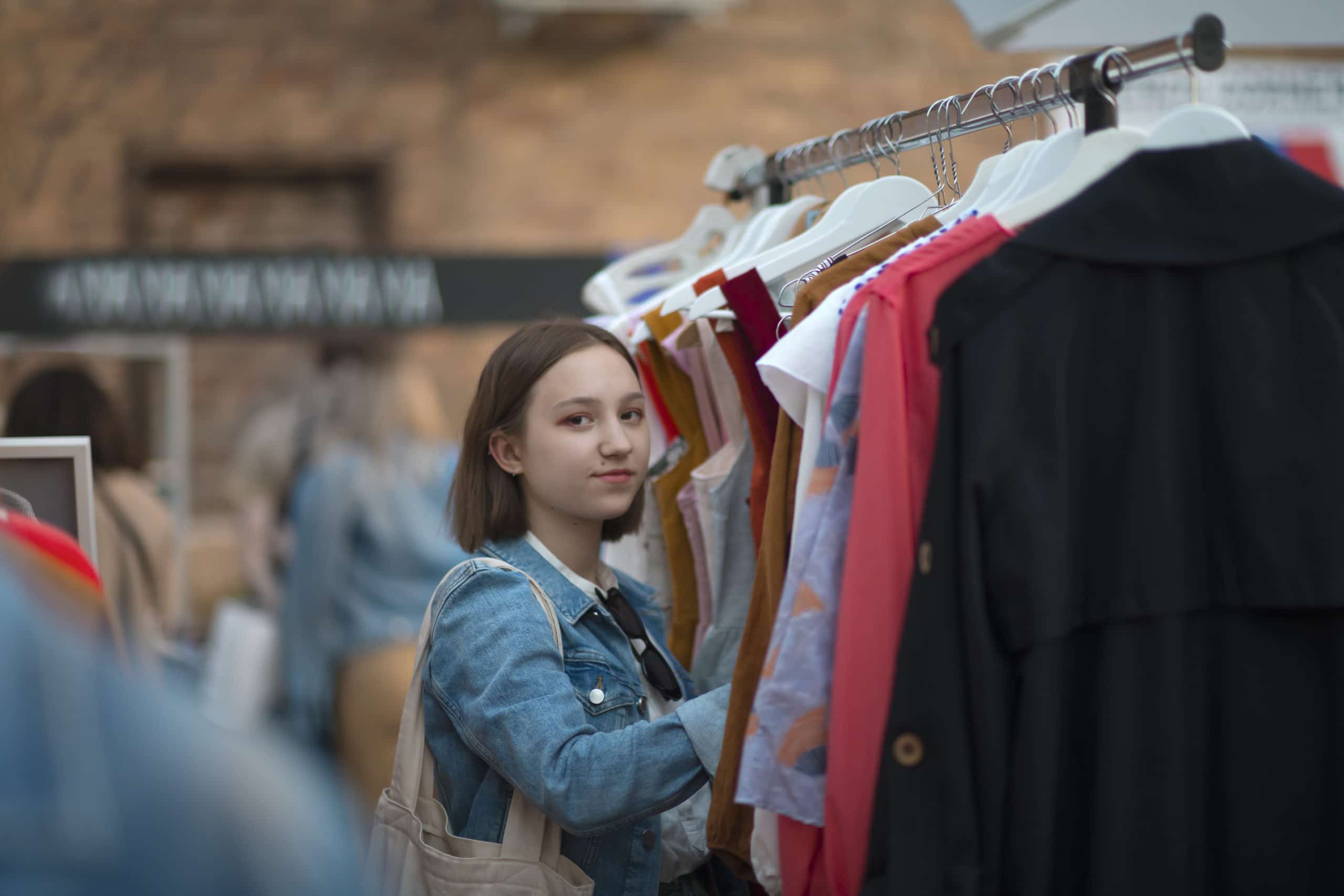 Nuori nainen shoppailemassa vaatteita kirpputorilla.